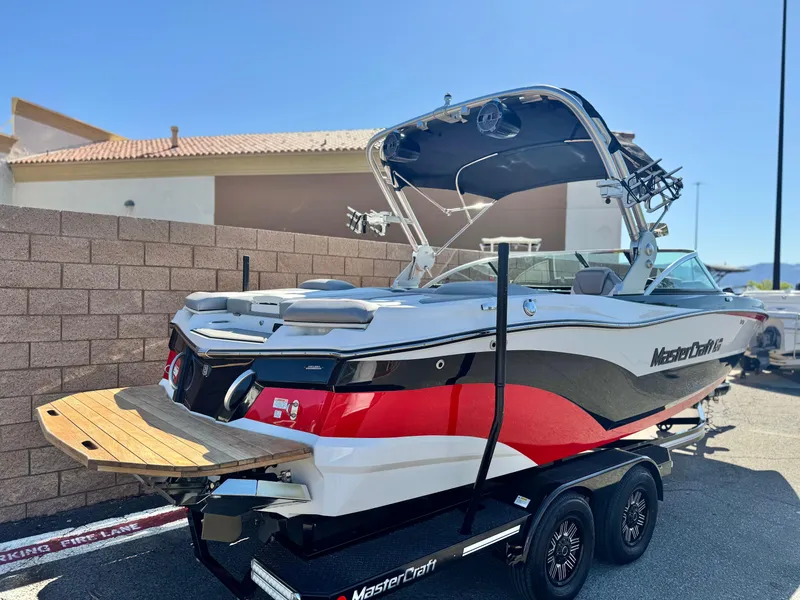 Slide: The Image of 2018 MasterCraft XT22 boat on trailer, red and white design, parked outdoors. - 5