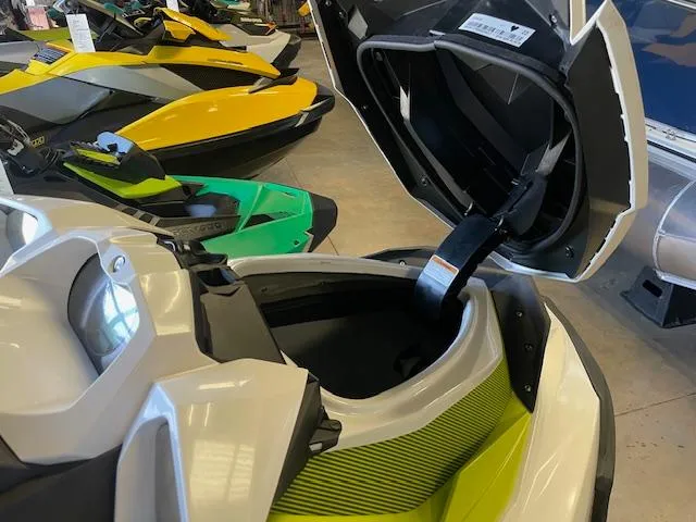Slide: The Image of 2017 Sea-Doo GTI with open storage compartment, surrounded by colorful jet skis in showroom. - 5