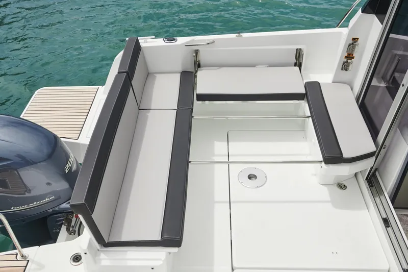 Slide: The Image of 2025 Jeanneau NC795 S2 boat deck with cushioned seating and outboard motor. - 9