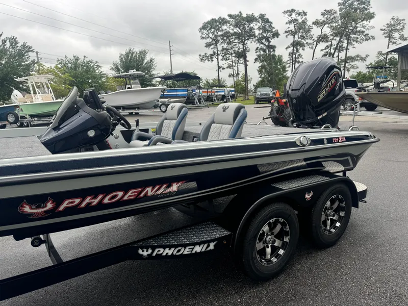 Slide: The Image of 2025 Phoenix 721 ZXL boat with dual seats and powerful outboard motor, parked outdoors. - 2