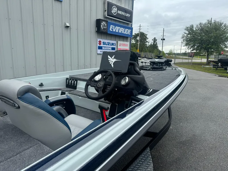 Slide: The Image of 2025 Phoenix 721 ZXL boat with steering wheel, parked near marine dealership signs. - 7
