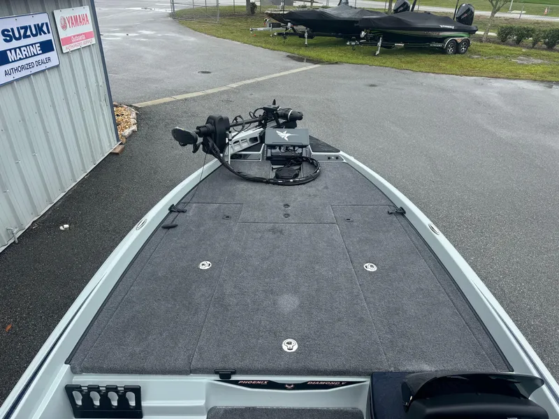 Slide: The Image of 2025 Phoenix 721 ZXL boat with spacious deck, parked near Suzuki Marine dealership. - 8