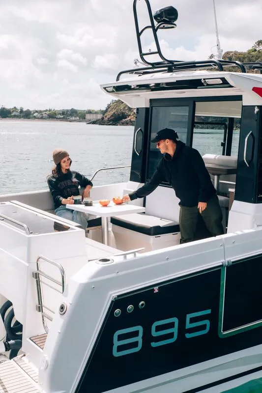 Slide: The Image of 2025 Jeanneau NC895 Sport S2 boat with people enjoying drinks on deck. - 4