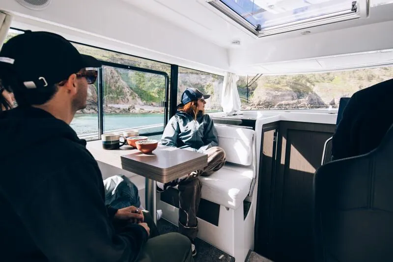 Slide: The Image of People relaxing inside a 2025 Jeanneau NC895 Sport S2 boat, enjoying scenic views. - 5