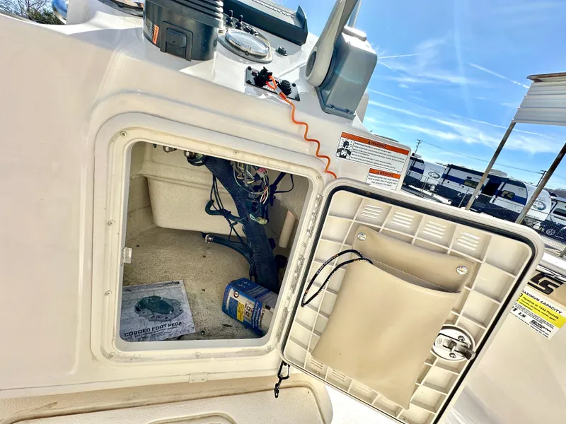Slide: The Image of 2021 Carolina Skiff 21 LS boat storage compartment with open hatch, showing wiring and equipment. - 27