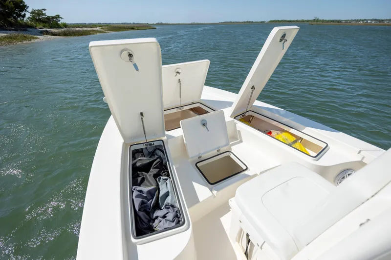 Slide: The Image of 2023 Pathfinder 2300 HPS boat with open storage compartments on calm water. - 11