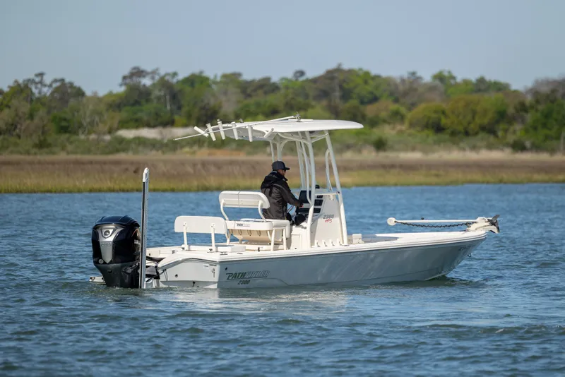 Slide: The Image of 2023 Pathfinder 2300 HPS boat cruising on a calm lake with lush greenery in the background. - 4