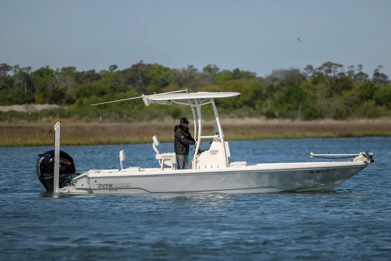 Slide: The Image of 2023 Pathfinder 2300 HPS boat on water, person standing, lush green shoreline in background. - 5