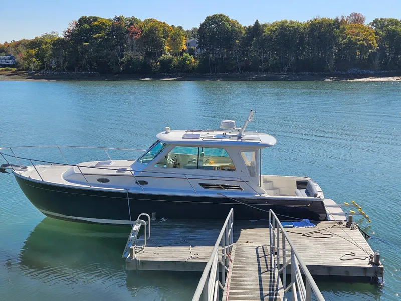 Slide: The Image of 2008 Back Cove 33 Express boat docked on calm water with forested shoreline. - 38