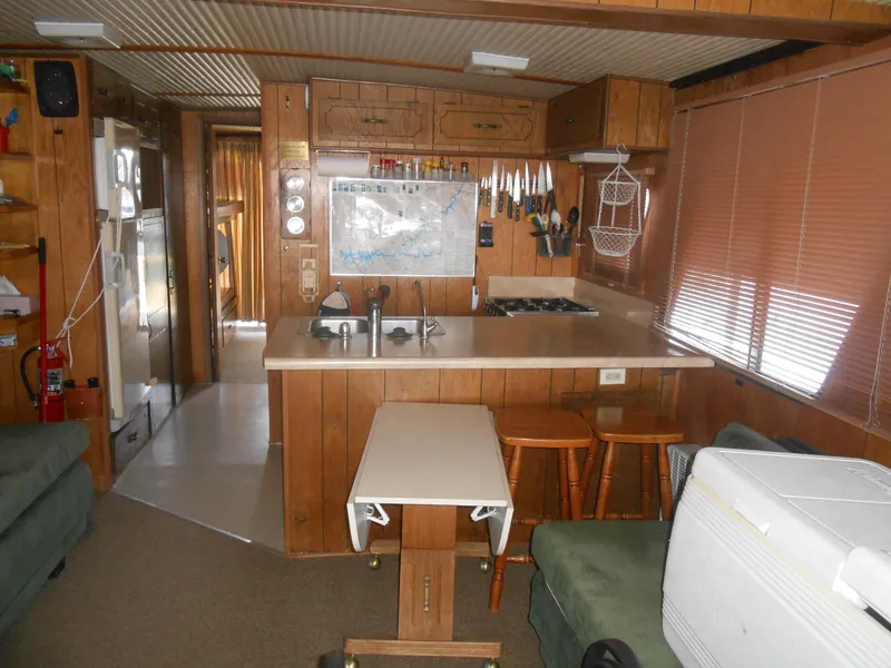 Slide: The Image of Interior of a 1984 Boatel Hercules houseboat with wooden cabinetry and compact kitchen area. - 12