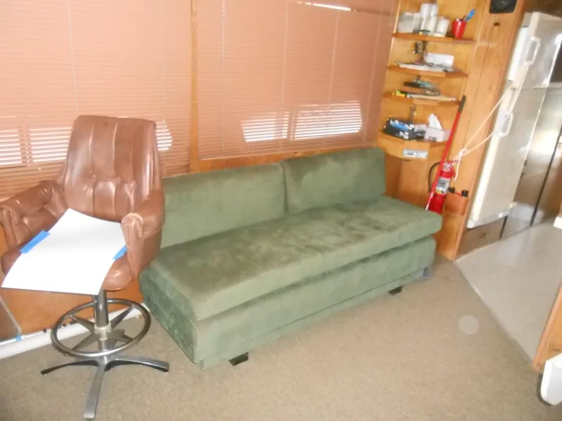 Slide: The Image of Interior of 1984 Boatel Hercules with green sofa, brown chair, and wooden shelves. - 13