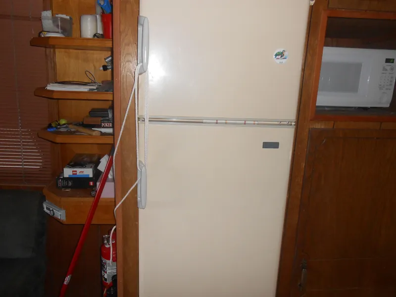 Slide: The Image of 1984 Boatel Hercules interior with refrigerator, microwave, and wooden shelves. - 16