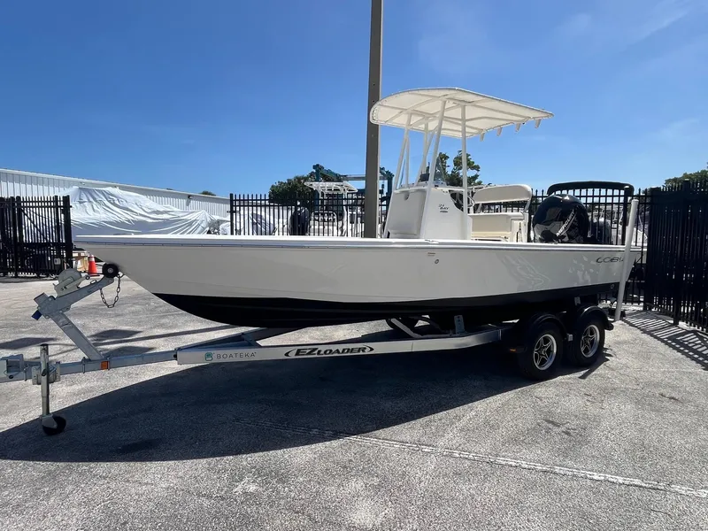 Slide: The Image of 2021 Cobia 21 Bay boat on trailer, parked outdoors under clear blue sky. - 2