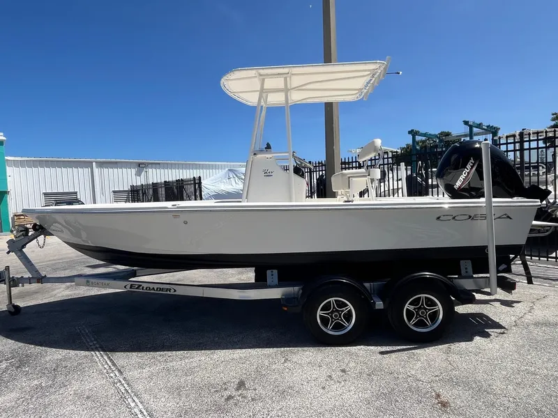 Slide: The Image of 2021 Cobia 21 Bay boat on trailer, parked outdoors under clear blue sky. - 3