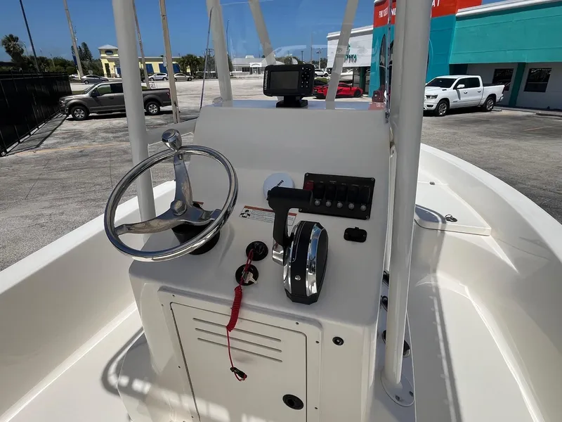 Slide: The Image of 2021 Cobia 21 Bay boat console with steering wheel and controls, parked outdoors. - 6