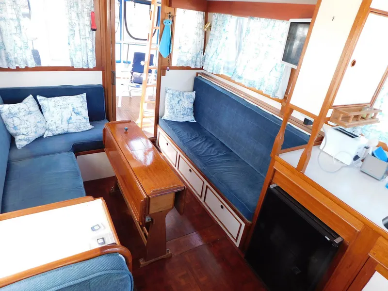 Slide: The Image of 1979 Grand Banks 32 Sedan interior with blue seating, wooden table, and nautical decor. - 11