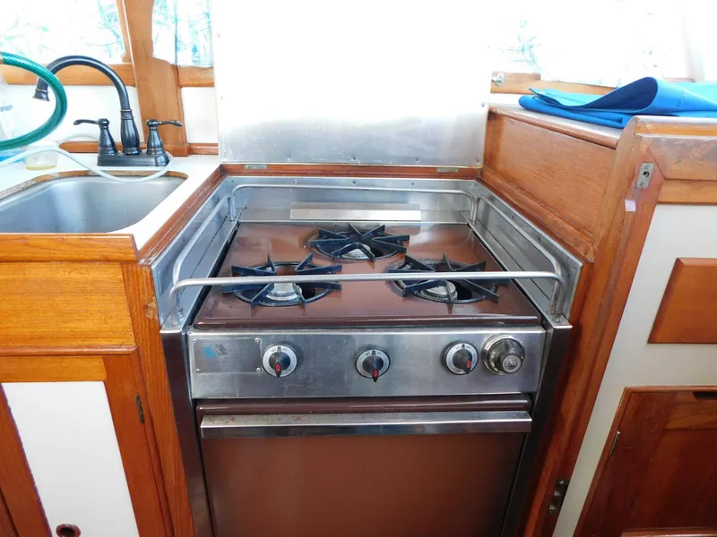 Slide: The Image of 1979 Grand Banks 32 Sedan kitchen with stove and sink, featuring wooden cabinetry. - 12