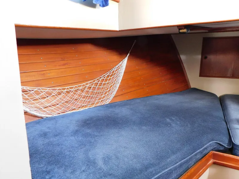 Slide: The Image of 1979 Grand Banks 32 Sedan cabin interior with blue bedding and wooden paneling. - 15