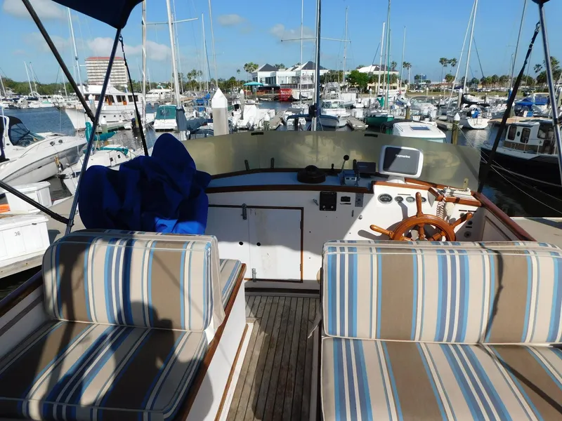 Slide: The Image of 1979 Grand Banks 32 Sedan boat interior with striped seating at a marina. - 20