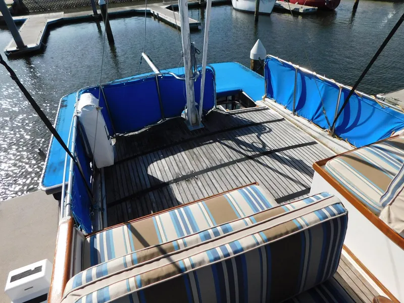Slide: The Image of 1979 Grand Banks 32 Sedan boat deck with striped seating and blue protective covers. - 26
