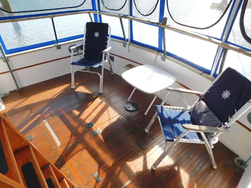 Slide: The Image of 1979 Grand Banks 32 Sedan boat deck with chairs and table, featuring blue accents and wooden flooring. - 31