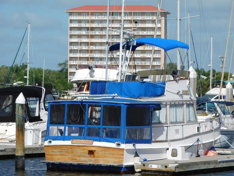 Slide: The Image of 1979 Grand Banks 32 Sedan docked at marina with blue canopy and nearby boats. - 33