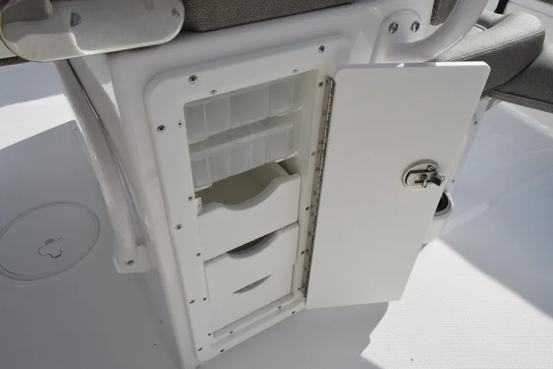 Slide: The Image of 2025 Sea Hunt Ultra 255 SE boat storage compartment with open door and drawers. - 15