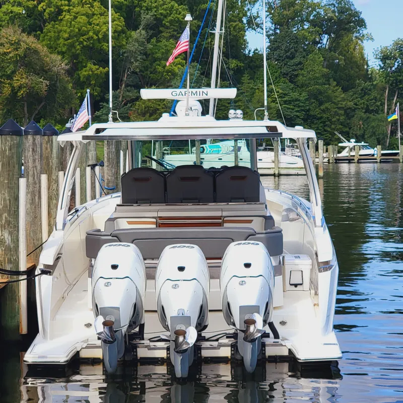 Slide: The Image of 2021 Tiara Yachts 38 LS with triple outboard engines docked in a marina. - 11