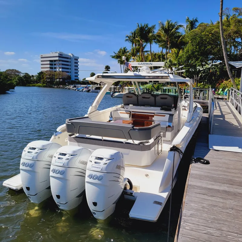 Slide: The Image of 2021 Tiara Yachts 38 LS docked, featuring triple 400 horsepower engines, surrounded by lush greenery. - 13