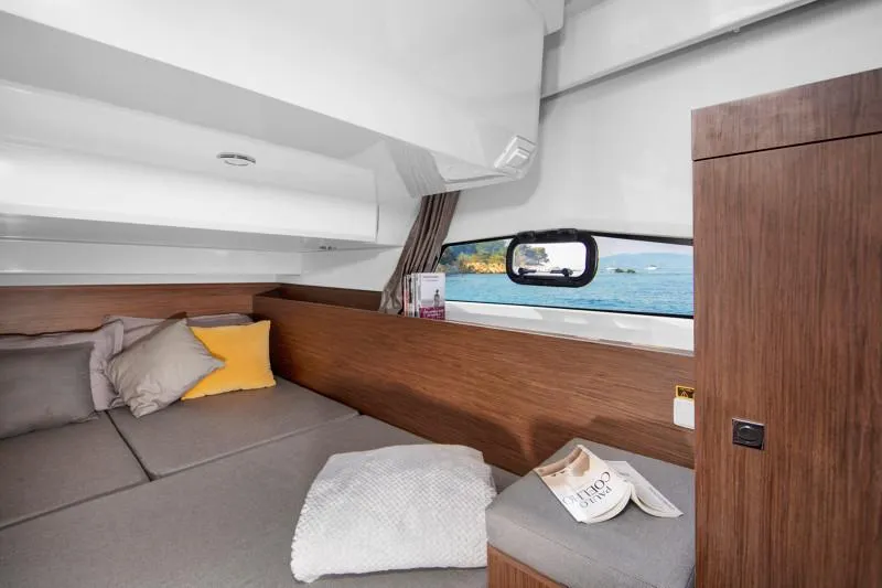 Slide: The Image of 2025 Jeanneau NC1095 Coupe cabin interior with cozy bedding and scenic window view. - 13
