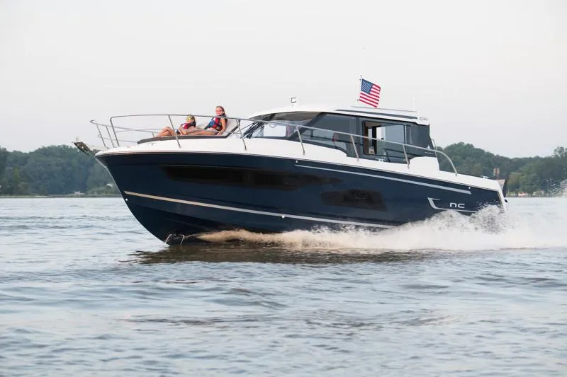 Slide: The Image of 2025 Jeanneau NC1095 Coupe cruising on a lake with passengers onboard. - 5