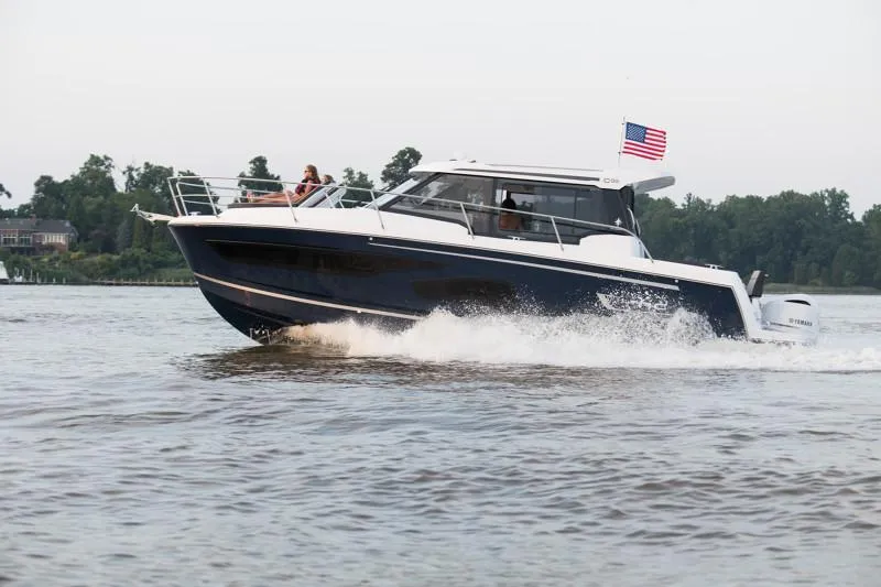 Slide: The Image of 2025 Jeanneau NC1095 Coupe cruising on a lake with an American flag. - 6