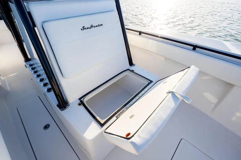Slide: The Image of 2014 SeaHunter 32 Tournament boat with open storage compartment, white seating, and ocean backdrop. - 13