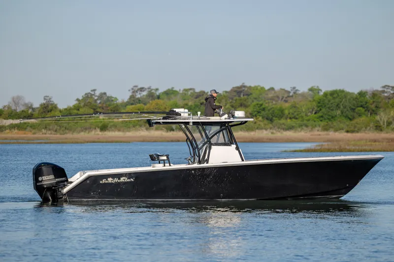 Slide: The Image of 2014 SeaHunter 32 Tournament boat on calm water with lush green shoreline. - 8
