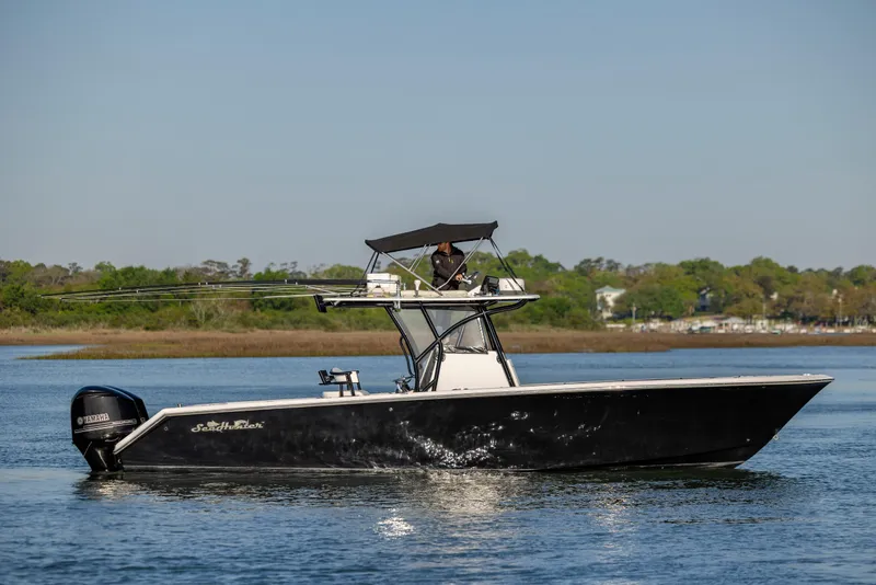 Slide: The Image of 2014 SeaHunter 32 Tournament boat on calm water with lush green shoreline. - 9