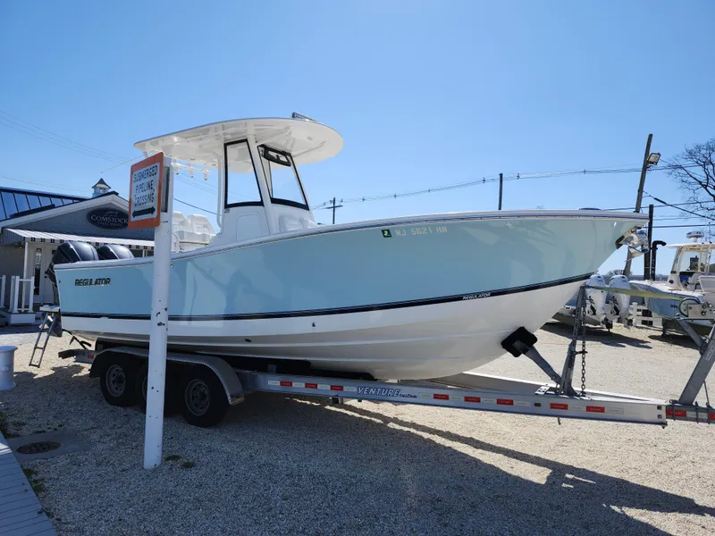 Slide: The Image of 2020 Regulator 25 boat on trailer, displayed outdoors under clear blue sky. - 1