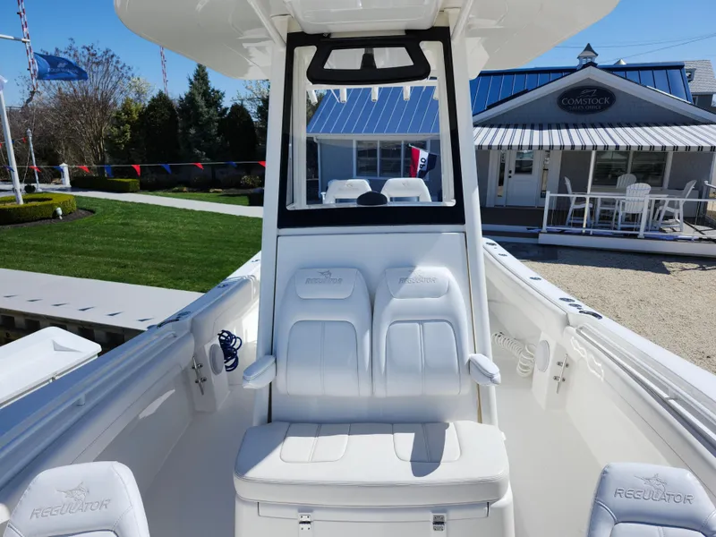 Slide: The Image of 2020 Regulator 25 boat interior with white seating and console, displayed outdoors. - 15