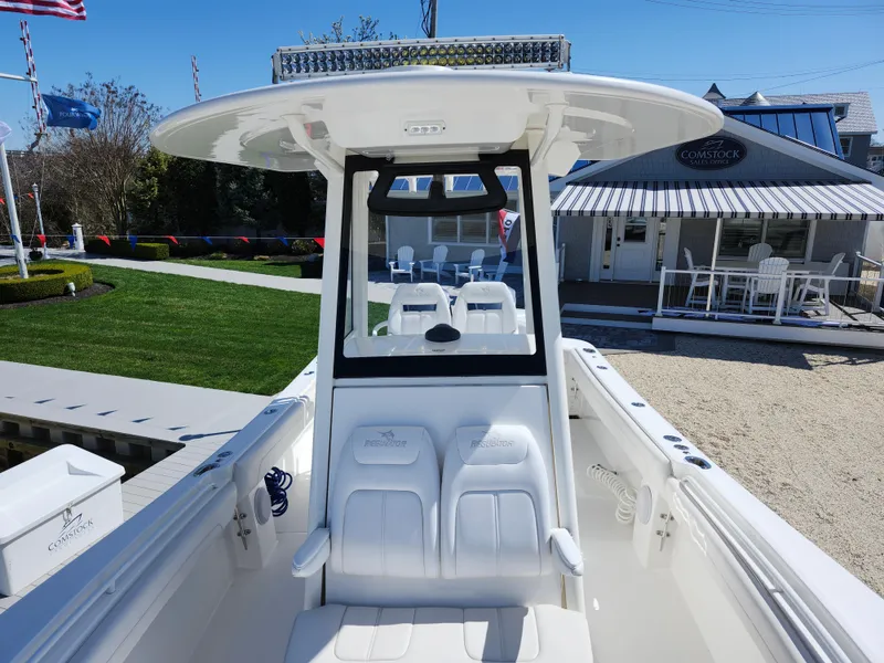 Slide: The Image of 2020 Regulator 25 boat with T-top and seating, displayed outdoors at a marina. - 16