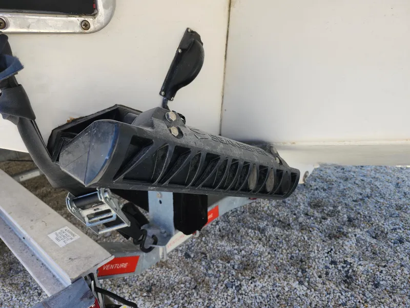 Slide: The Image of 2020 Regulator 25 boat trailer detail with black component and gravel ground. - 30