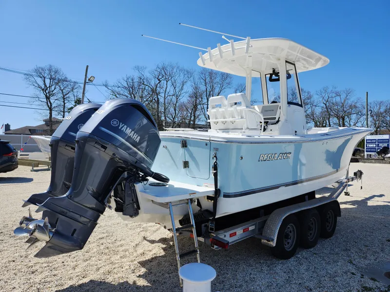 Slide: The Image of 2020 Regulator 25 boat with Yamaha engines on a trailer, parked outdoors. - 4