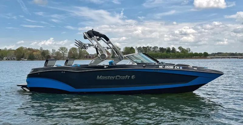 The Image of 2019 MasterCraft X24 boat on a lake under a partly cloudy sky. - 0