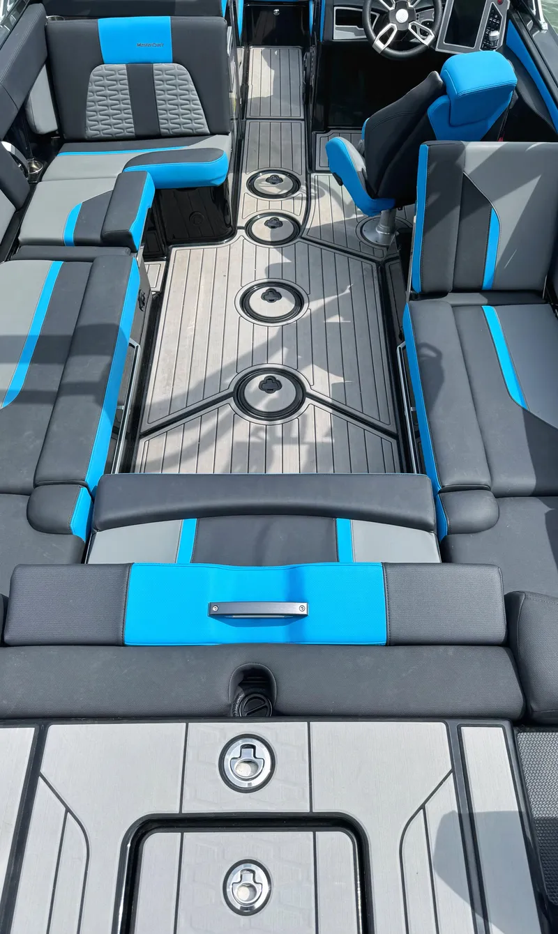 Slide: The Image of 2019 MasterCraft X24 boat interior with blue and gray seating, modern design, and spacious layout. - 2