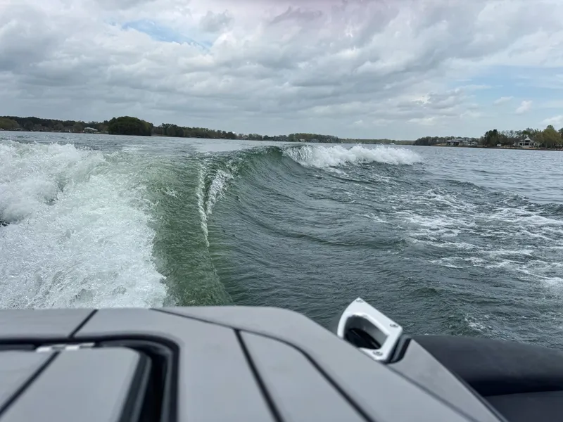 Slide: The Image of 2019 MasterCraft X24 creating waves on a lake under cloudy skies. - 3