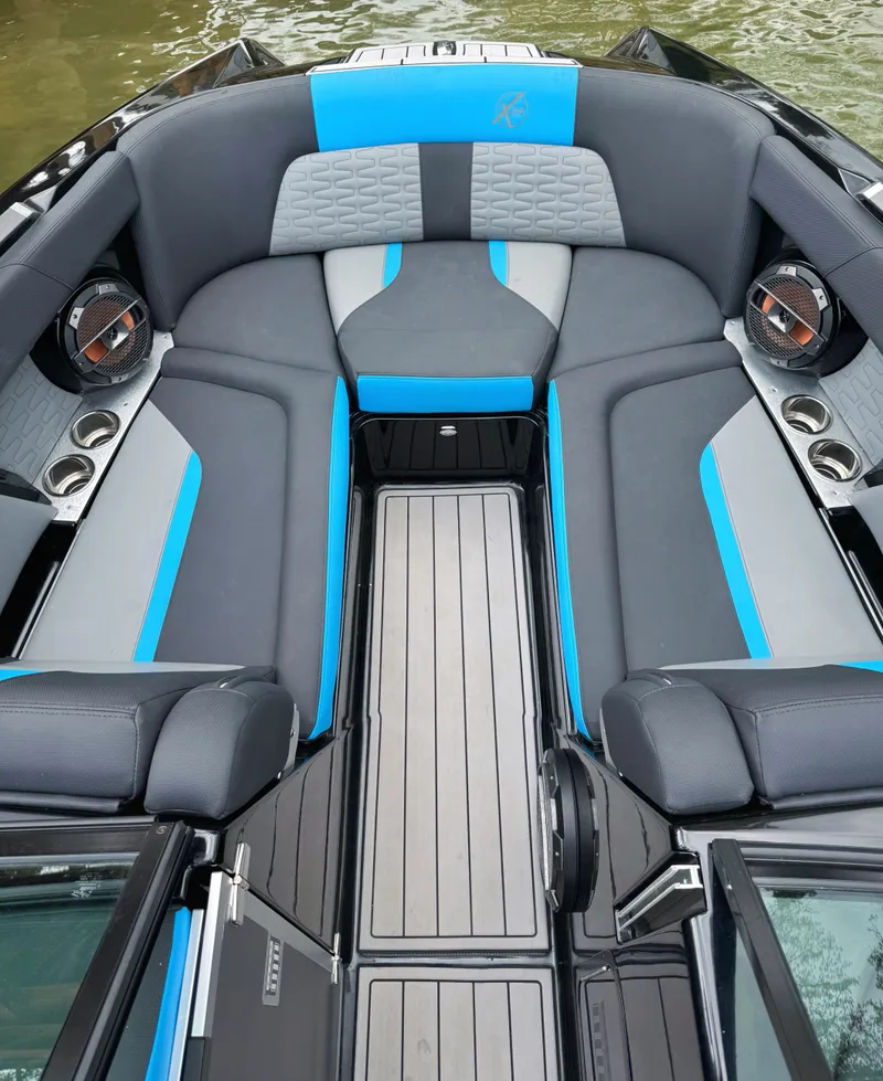 Slide: The Image of 2019 MasterCraft X24 boat interior with gray and blue seating, cup holders, and speakers. - 4