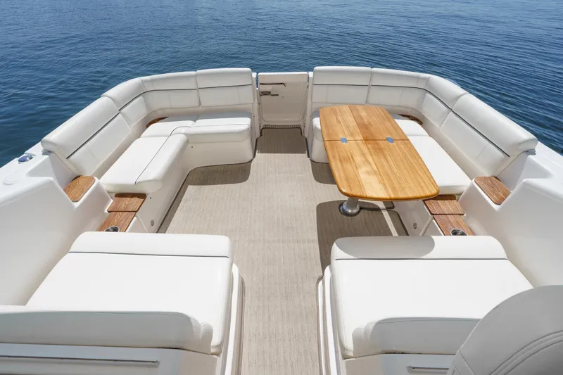 Slide: The Image of 2018 Tiara Yachts 3100 Coronet interior with white seating and wooden table on calm water. - 22