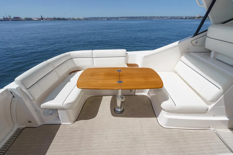 Slide: The Image of 2018 Tiara Yachts 3100 Coronet deck with white seating and wooden table, overlooking calm waters. - 26