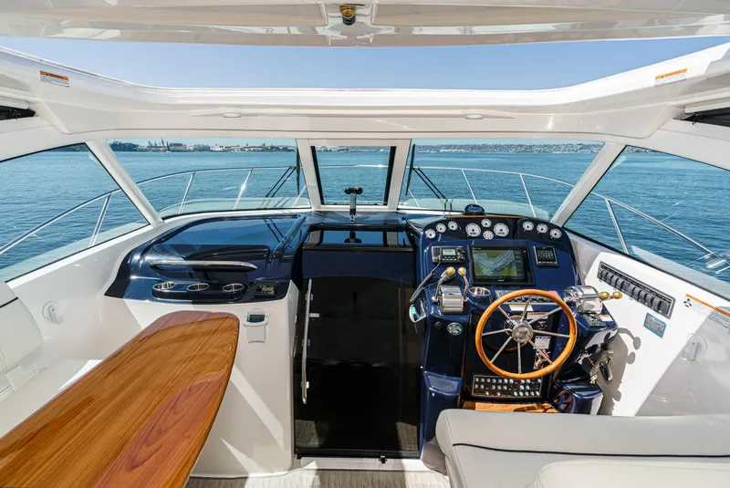 Slide: The Image of 2018 Tiara Yachts 3100 Coronet cockpit with wooden table, steering wheel, and navigation controls. - 35