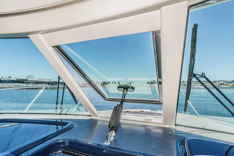 Slide: The Image of 2018 Tiara Yachts 3100 Coronet cockpit view with open window, overlooking serene waters. - 48