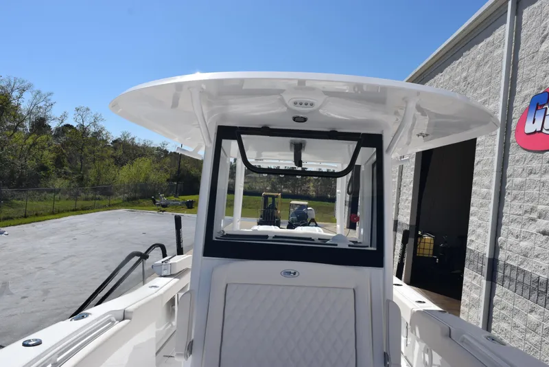 Slide: The Image of 2025 Sea Hunt Gamefish 28 boat, white exterior, docked near a building under clear blue sky. - 15