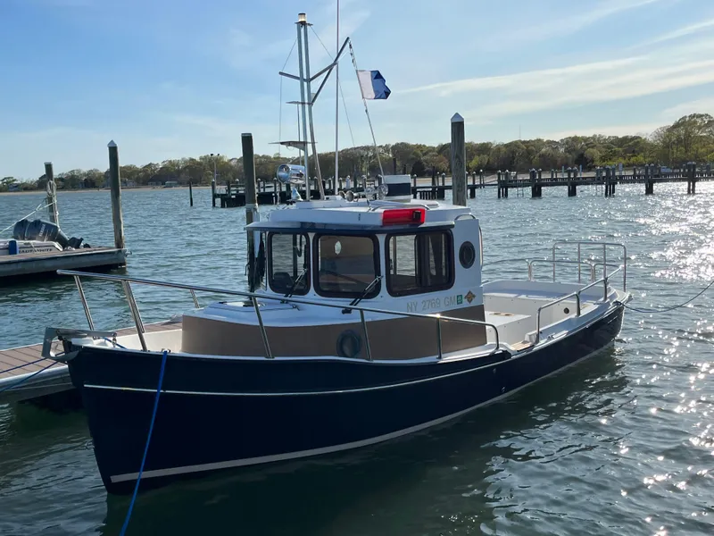 Slide: The Image of 2013 Ranger Tugs R-21 EC boat docked in a marina, calm water, clear sky. - 2